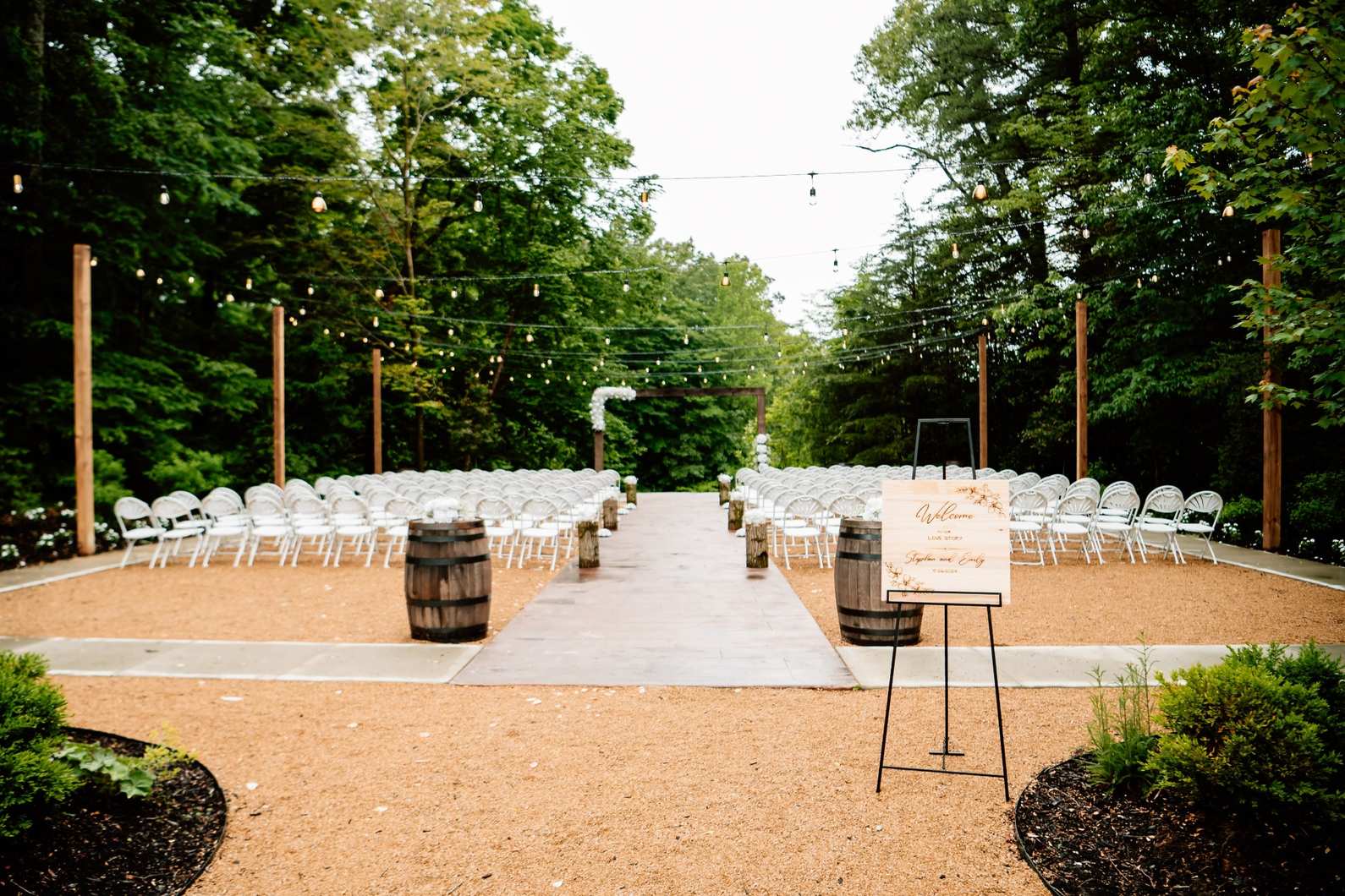 Ceremony aisle with welcome sign and wooded backdrop in Oregon
