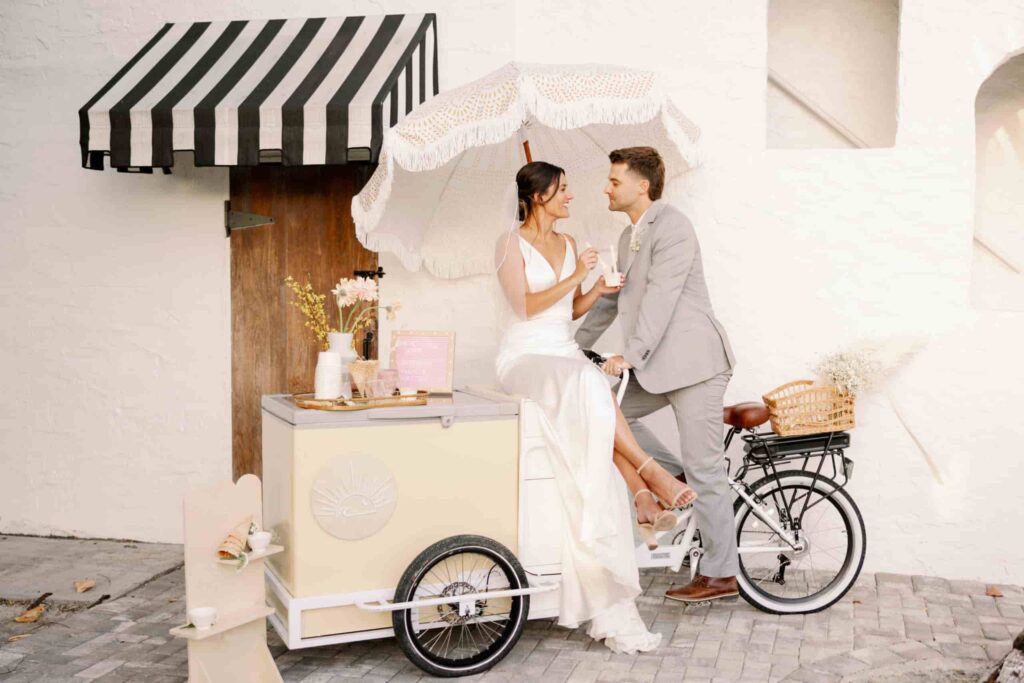 Couple next to ice cream cart with parasol curated by San Diego wedding planner