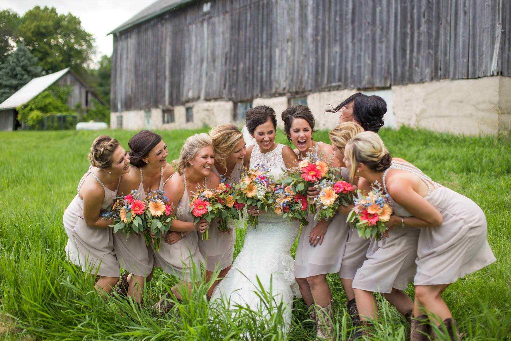 Bride and bridesmaids posing outside rustic barn wedding venue in Wichita