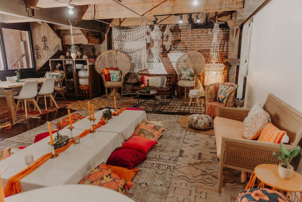 A colorful and whimsical bohemian event space with multiple seating areas, including a low table with pillow seats on the floor
