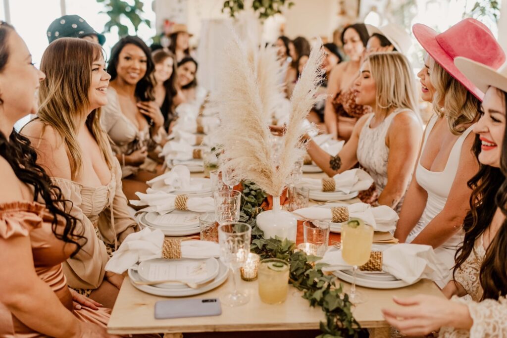 Women dressed in neutral tones gather around a long table decorated in bohemian style