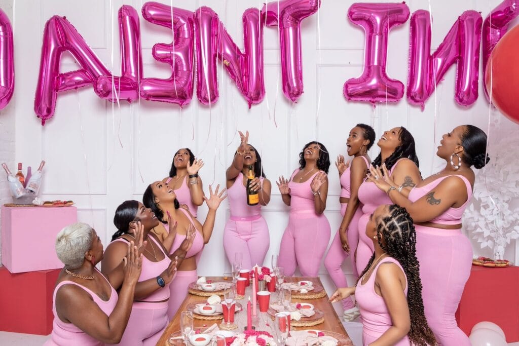 A group of women all dressed in pink pop champagne in celebration