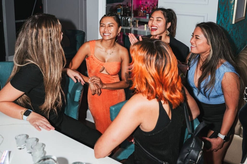 A group of women laugh together at a bar