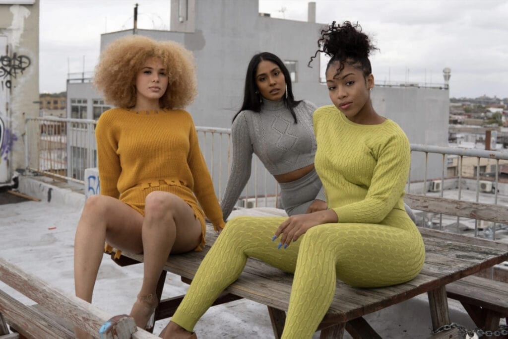 Three women sit on a picnic table on a rooftop