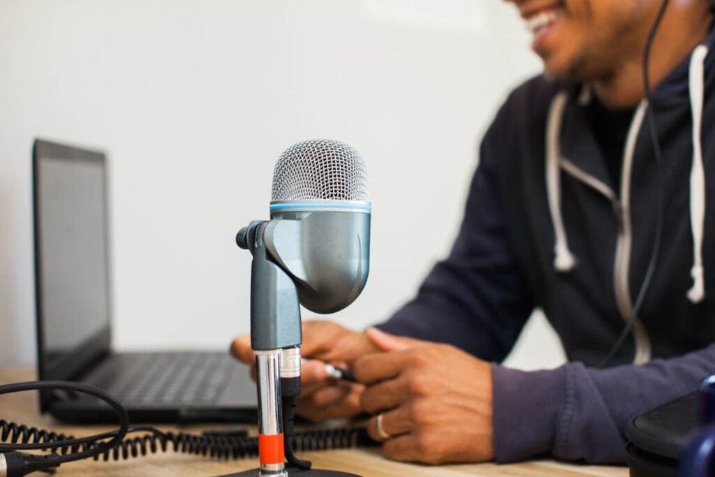 Closeup of a microphone sitting in front of a computer with a man's silhouette in the background