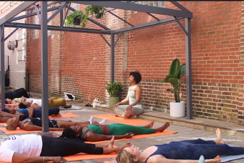 A yoga class takes place on a rooftop in an urban area