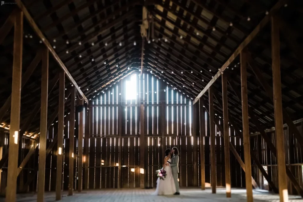 a couple in their wedding attire standing in a barn