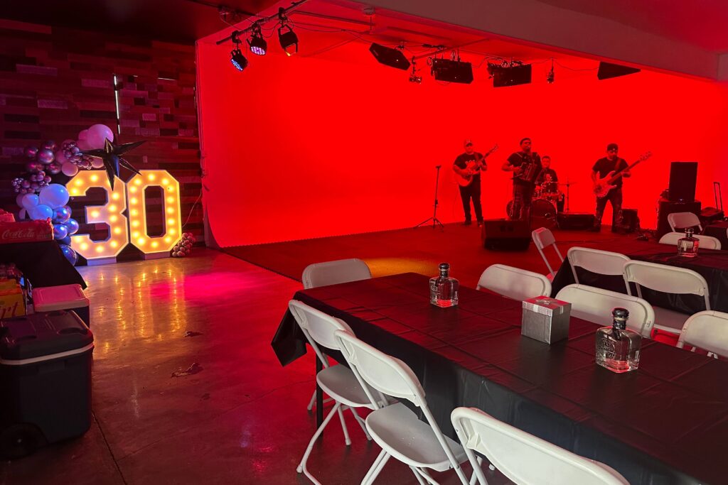 Event venue with a live band on stage and illuminated 30th birthday decorations