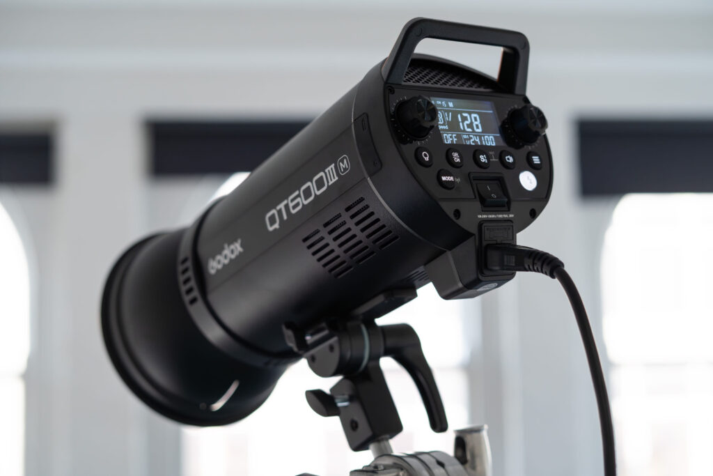 Close-up of a Godox QT600III M studio light on a stand in a professional photo studio setting.