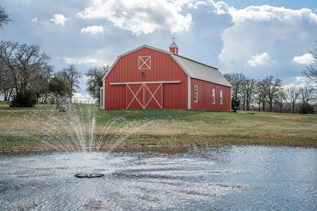 terracotta coloured barn with small pond outside