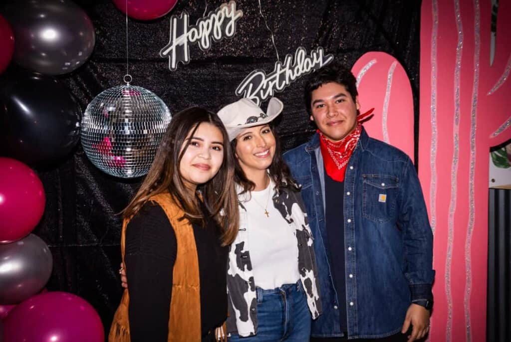 friends standing under a happy birthday sign