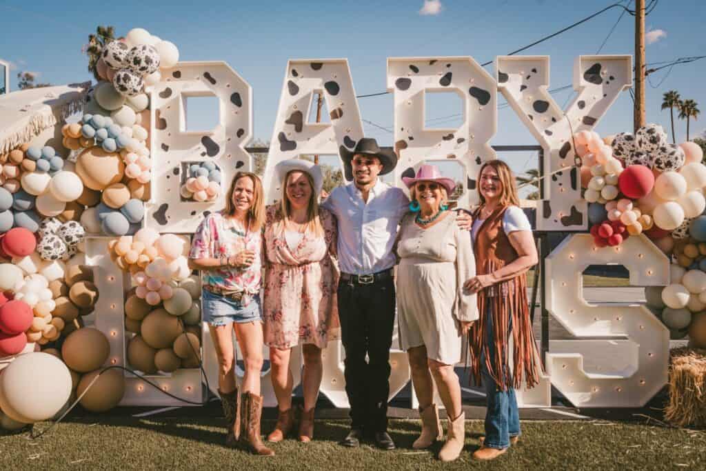 group standing in front of large sign spelling out baby