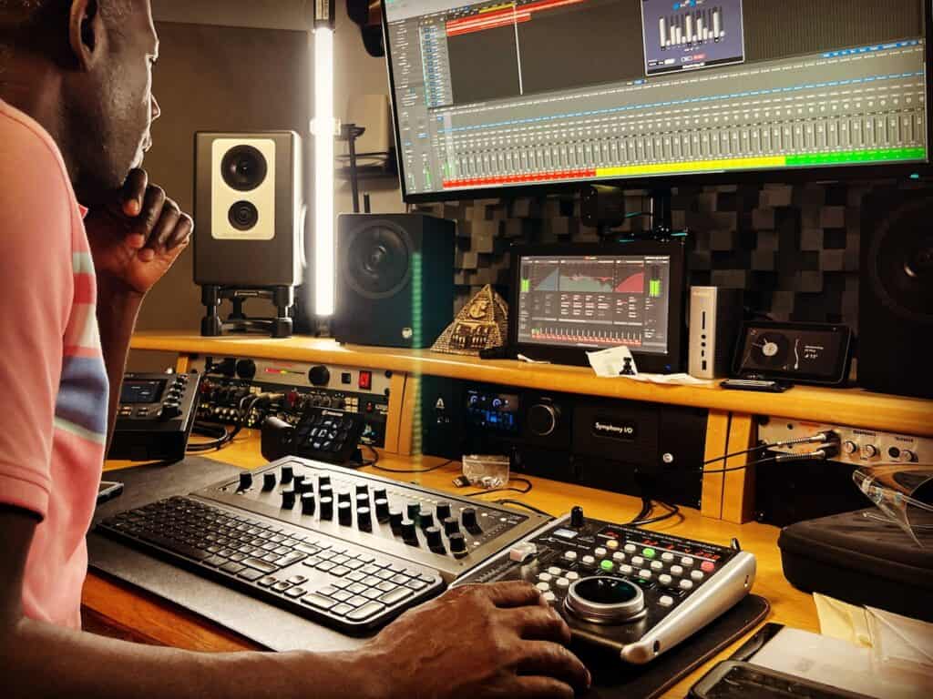 Producer working at mixing desk and monitors in a digital music studio.