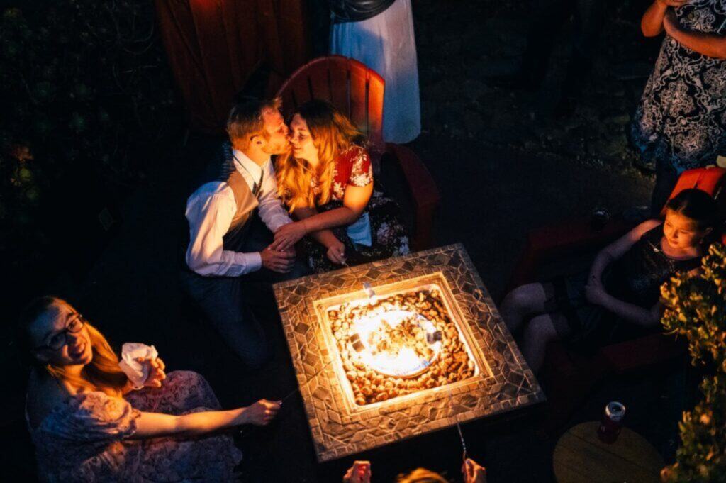 couple kissing while around a firepit