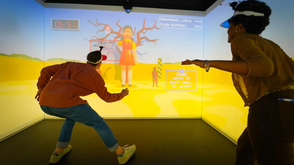 Squid Game The Experience London with two players in headbands competing in immersive Red Light Green Light game