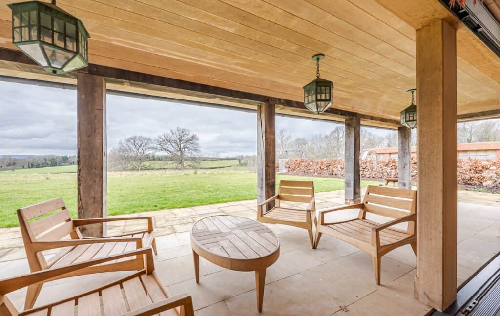 Covered patio at a stag party venue with wooden seating, lantern lights, and scenic countryside views.