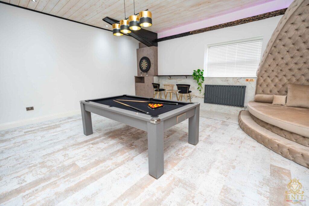 Stag party venue games room with pool table, dartboard, modern seating, and stylish lighting.