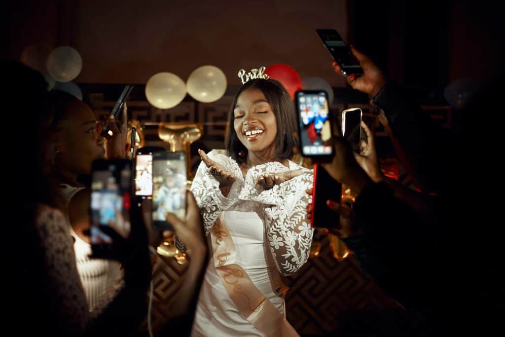 A bride-to-be being photographed with smartphones by her friends.