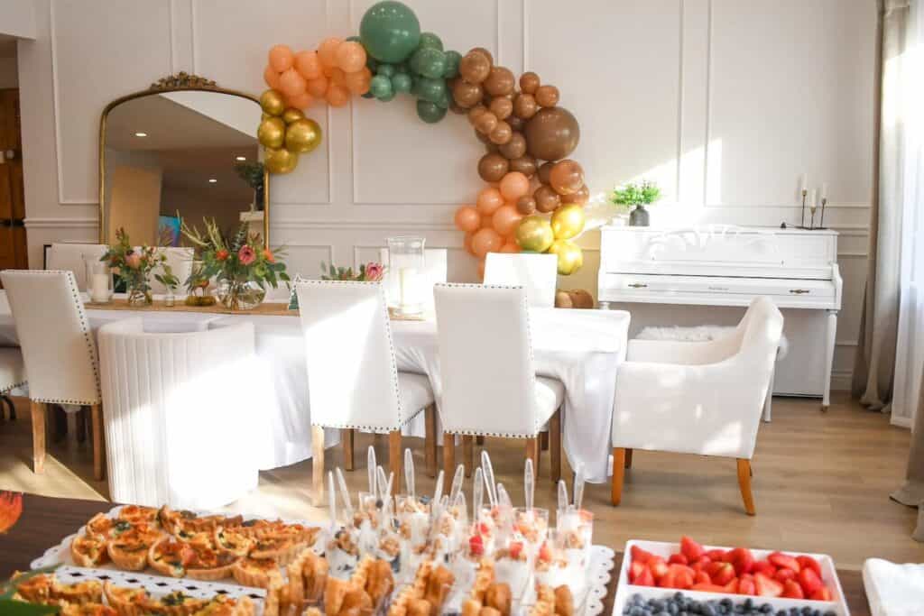 party food spread on a table with a balloons and seating in the background