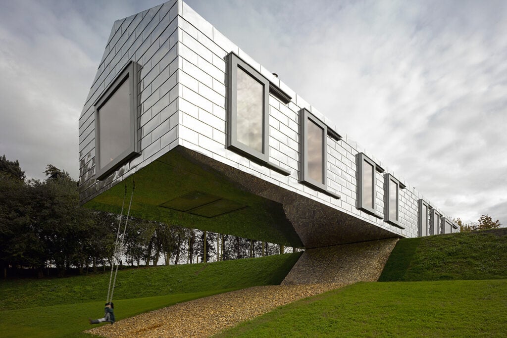 Balancing Barn cantilevered over a slope in Suffolk, clad in reflective steel tiles