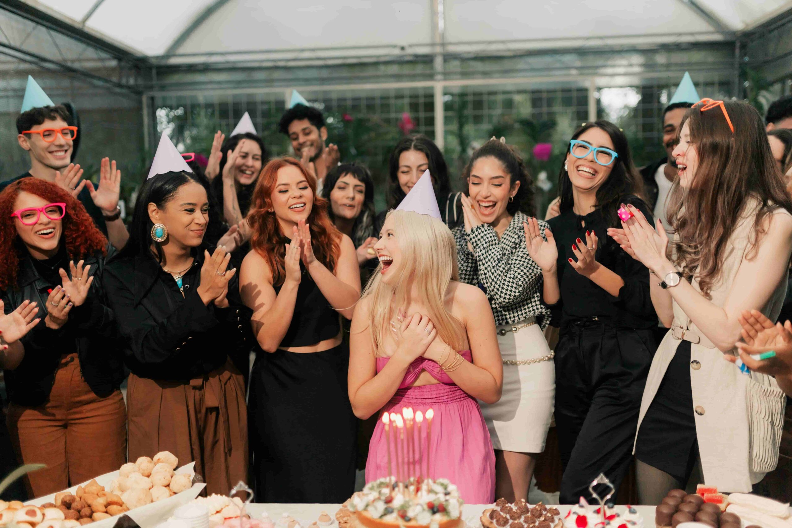 Birthday party with a woman in the center and clapping guests surrounding her.