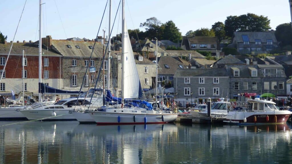 Boats and yachts docked on a harbour with stone houses in the background,