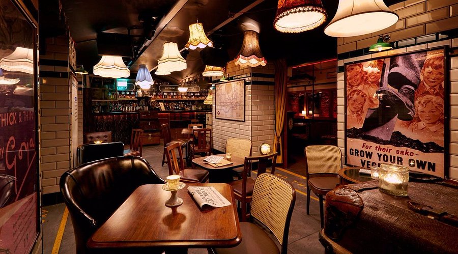Cahoots Underground London bar styled as a 1940s Tube station, with vintage lampshades, period posters and tiled walls