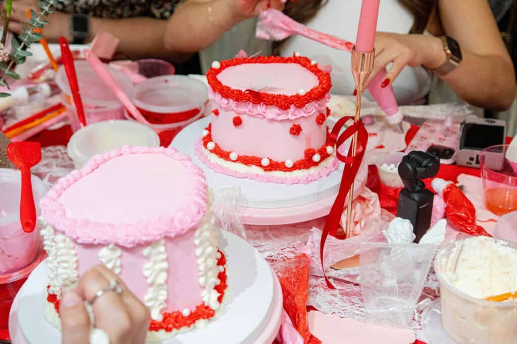 Women decorate heart-shaped cakes in a workshop.