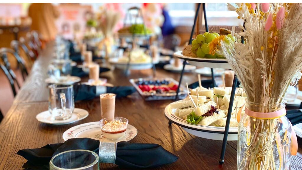 A long table with place sets featuring catered snacks and food items