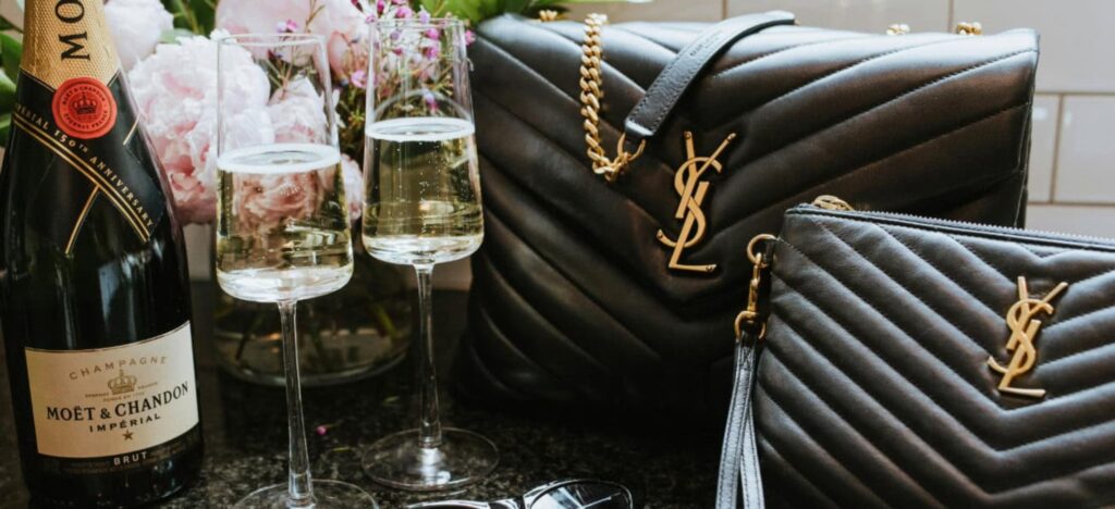 champagne bottle and designer handbags on a table