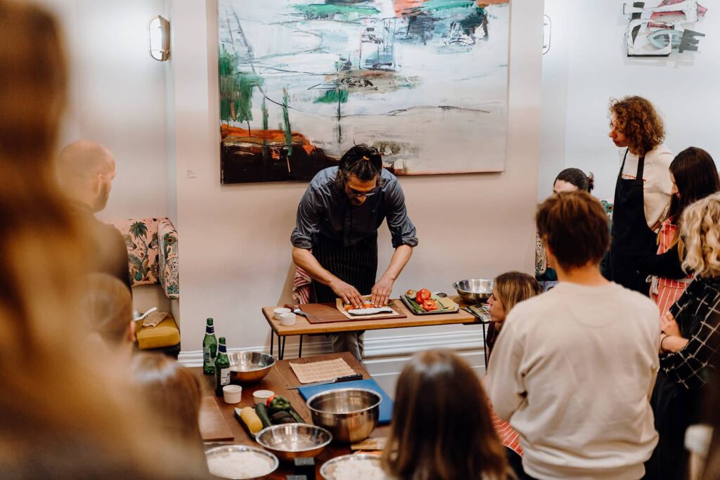 A sushi chef giving a cooking class to a group of people