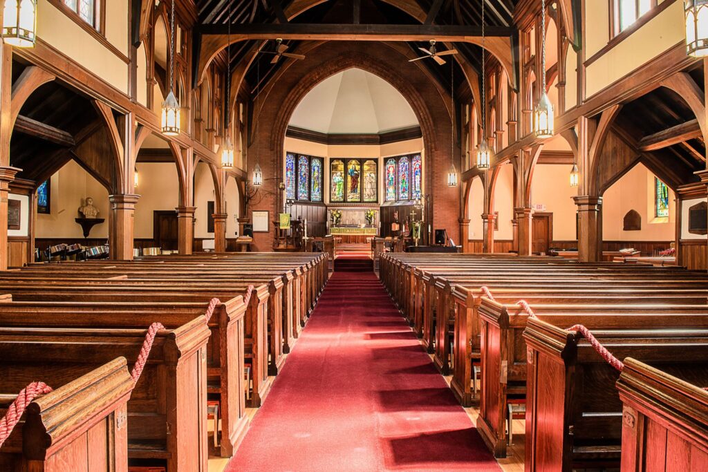 Traditional church with wood elements in the vaulted ceilings, red floors and stained glass.