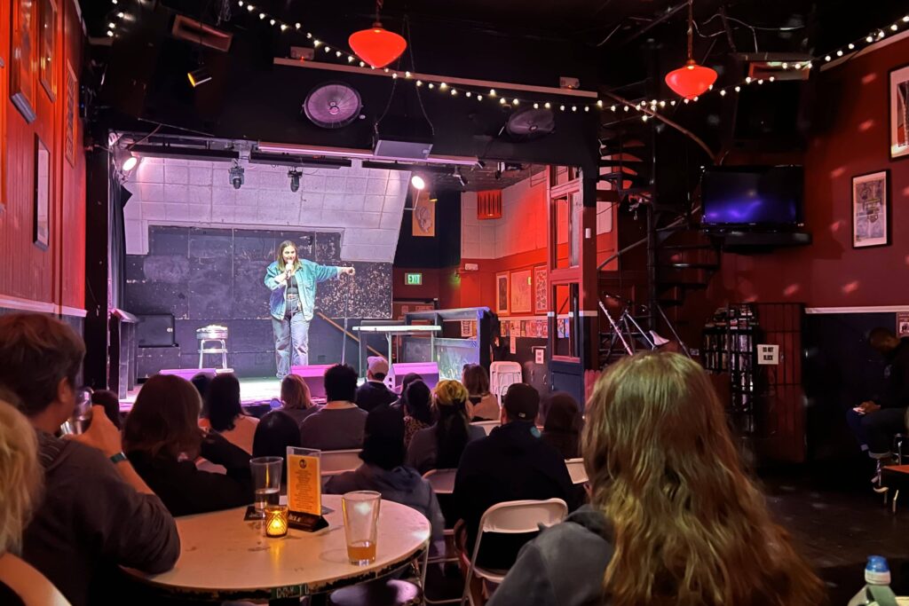 A comedian on stage performing for a crowd of spectators