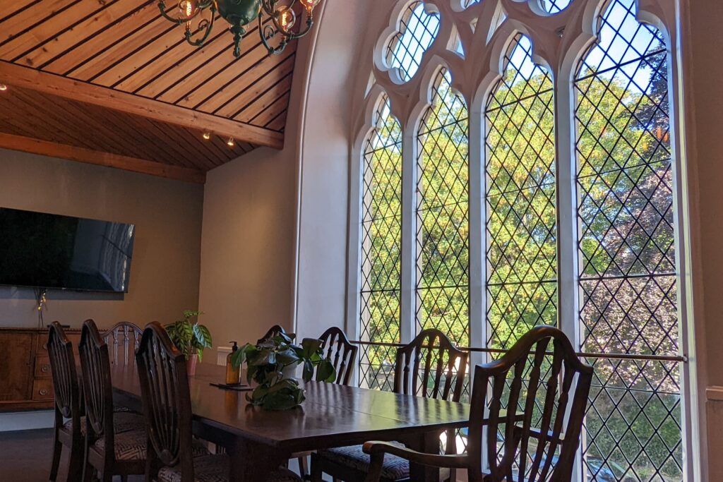 Room with a large table and large, ornate windows within a converted church building.