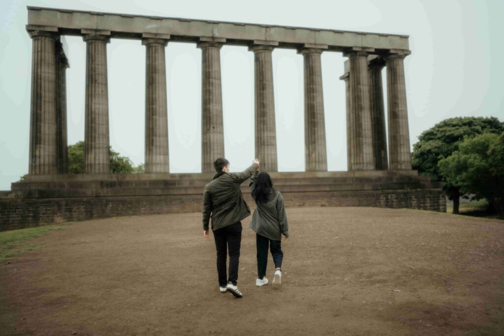Couple walking holding hands in front of historic pillars