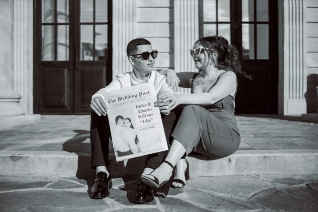 couple holding an engagement announcement sitting on steps