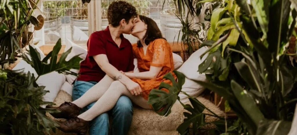 couple kissing on a sofa surrounded by plants
