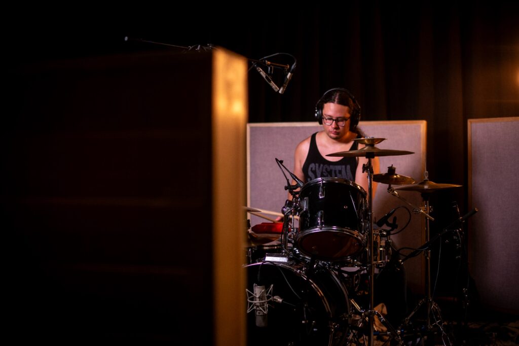 Drummer recording a song in a professional studio.