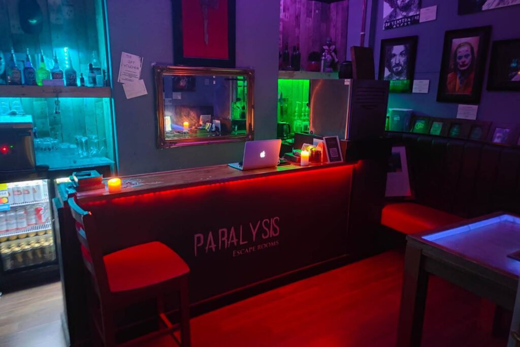 View of the reception desk of a dimly lit escape room venue in the UK called "Paralysis"