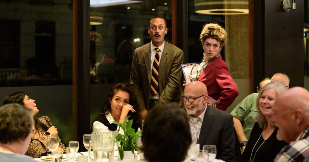 Faulty Towers The Dining Experience London with actors playing Basil and Sybil performing in character at a guests' dinner table