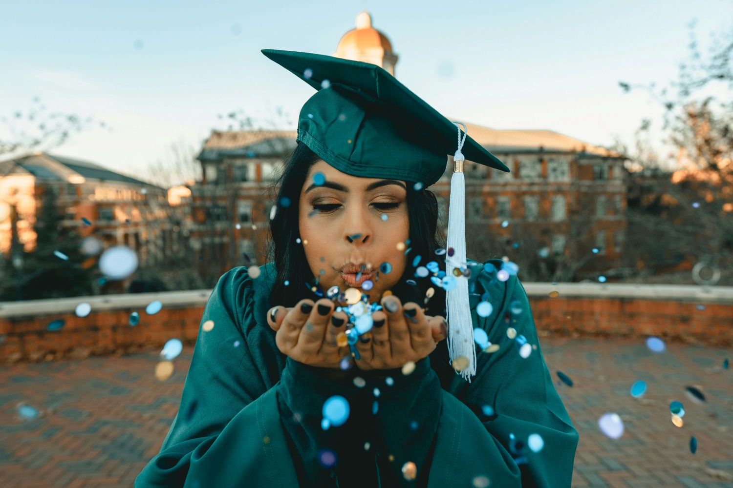 female graduate blowing on confetti