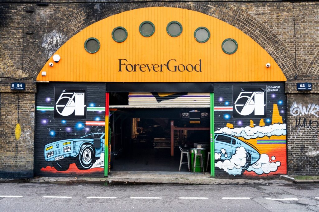 Exterior of ForeverGood Garage 54 in London with bold street art murals on a railway arch