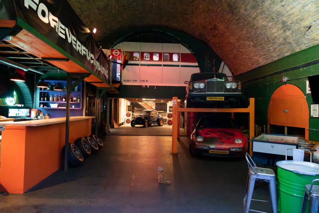 ForeverGood garage venue in London featuring vintage cars, a bar and railway arch architecture