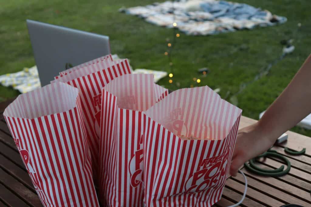 Three bags of popcorn on an outdoor table with a Macbook.