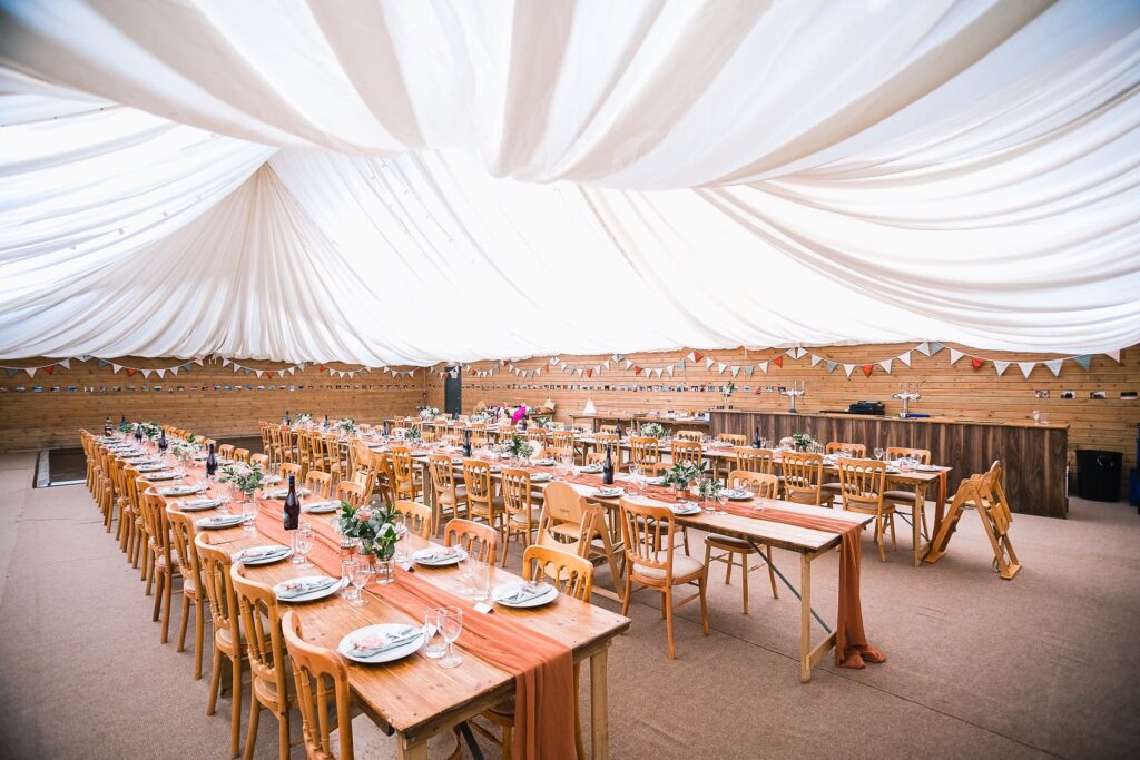 Event venue with long, decorated tables, bunting, and a white draped ceiling