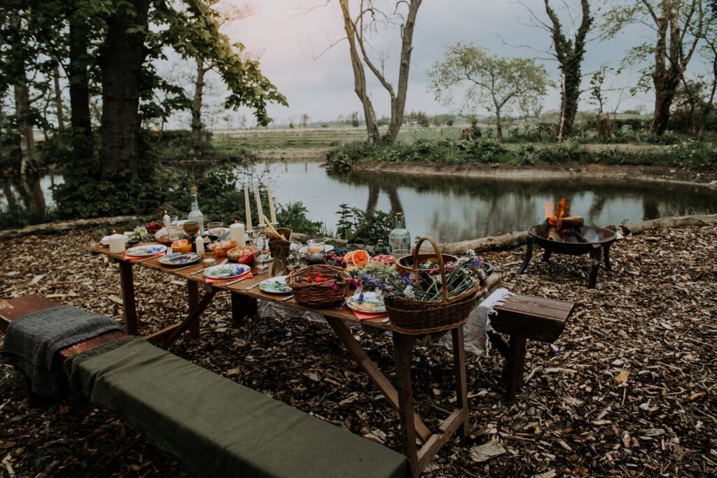 Long table set up for a outdoor gathering with food next to a lake in nature