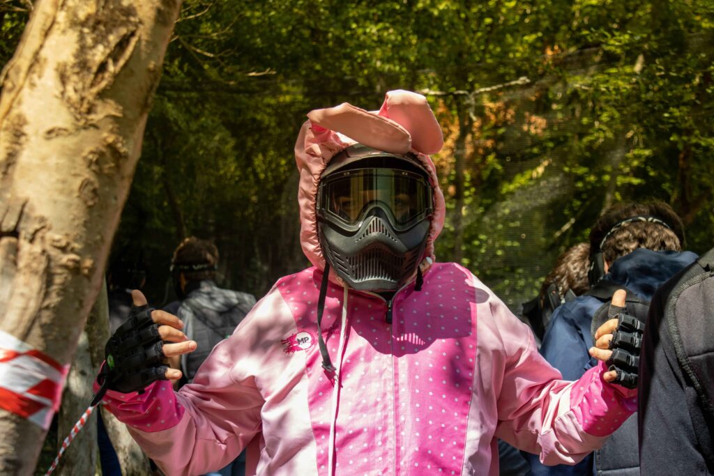 A man playing paintball dressed in a protective suit with mask