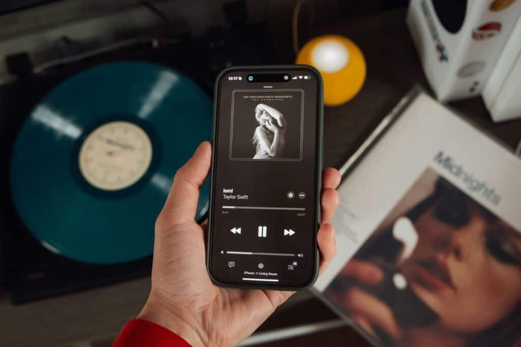 A hand holding a phone that plays a Taylor Swift song.