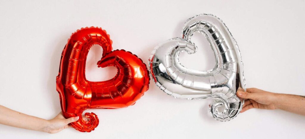 two heart balloons in silver and red next to each other
