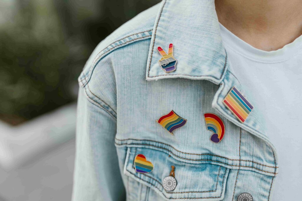 A jean jacket with rainbow flag pins.